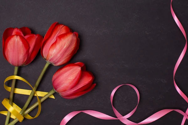 Lavagna nera pulita vuota con tulipani e nastri rossi. Vista dall'alto . — Foto Stock