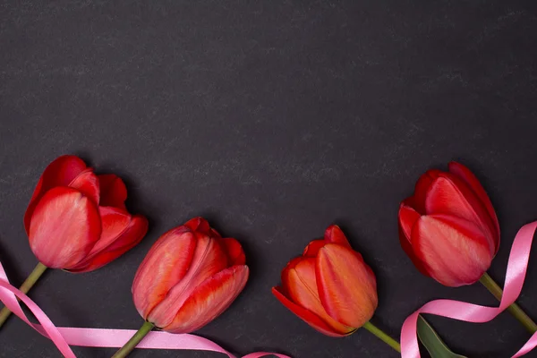 Lavagna nera pulita vuota con tulipani e nastri rossi . — Foto Stock