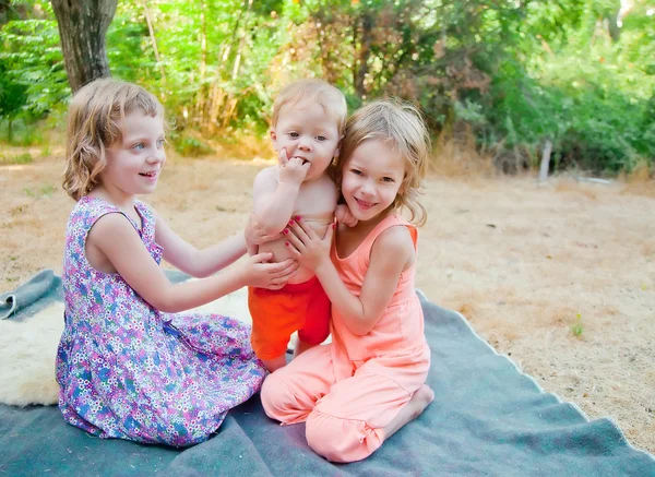 Twee zusters houden een broer — Stockfoto