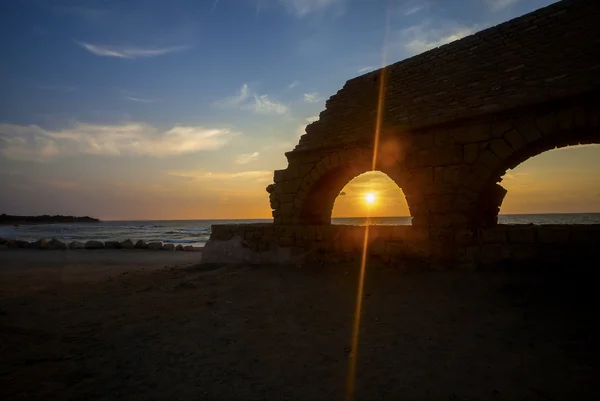 View of sinking sun through aqueduct arch — Stock Photo, Image