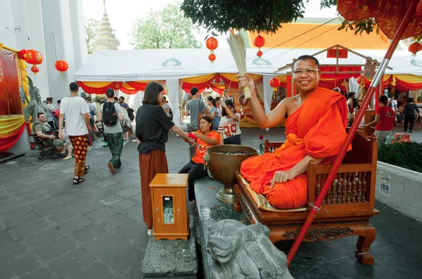 Monge asperge visitantes do templo de água benta dentro do famoso mosteiro Wat Pho — Fotografia de Stock