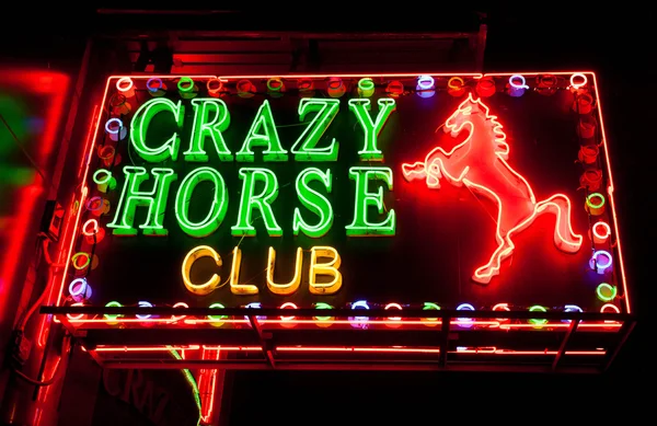 Neon lights sign of bar Crazy Horse Club on night street