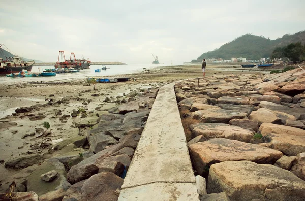 Riverbank with fishermen boats in shallow water with big stones and swamp — Stock Photo, Image