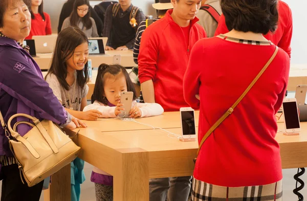 Unidentified girls using smartphone inside iStore with many iPhones and gadgets — Stock Photo, Image