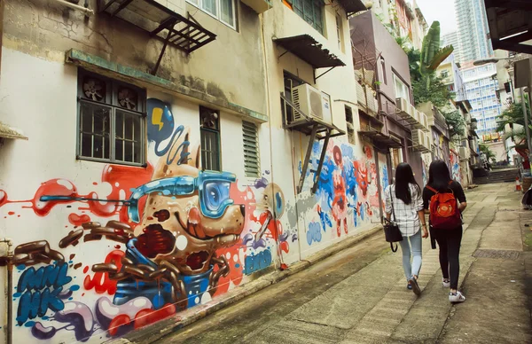 Две женщины идут по узкой улочке с уличным искусством в большом городе — стоковое фото