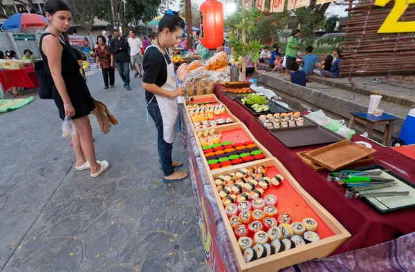 Clientes de mercado callejero observando comida, aperitivos y sushi con mariscos en patio de comida rápida —  Fotos de Stock