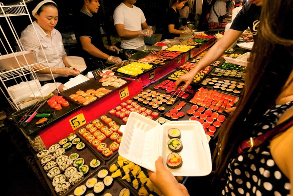 Sushi magasin extérieur vendant des spécialités de fruits de mer pendant le marché de nuit avec fast food court — Photo