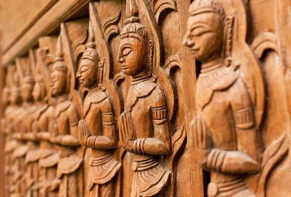 Carved wooden sculpture of praying Buddha in a line of different prayers — Stock Photo, Image