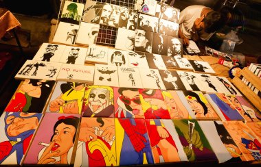 Sanat tüccarı gece pazarının satmak çok sayıda renkli popüler sanat resim film ve çizgi film kahramanları ile