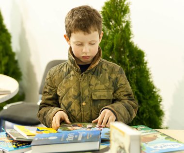 Unidentified boy carefully reads books at children showcase