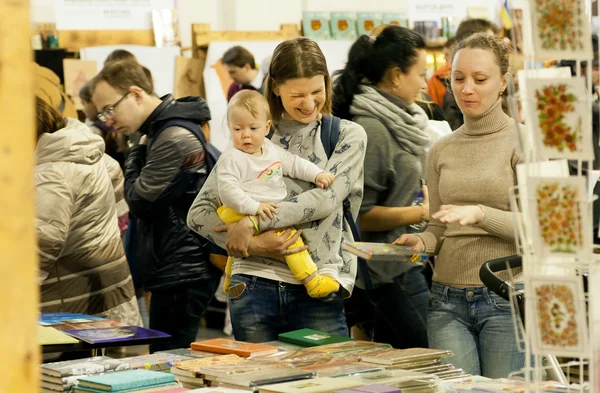 Неопознанный ребенок и счастливая молодая мама делают выбор на книжном фестивале — стоковое фото