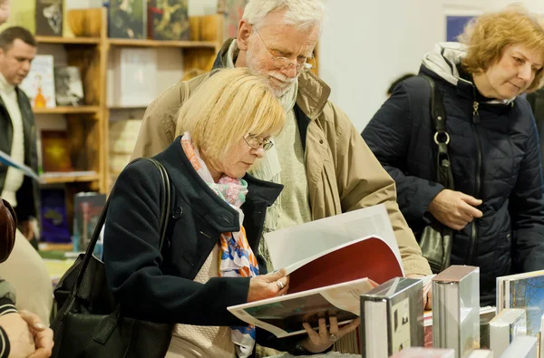 Personas mayores inteligentes leyendo nuevos libros con interés en el festival del libro — Foto de Stock