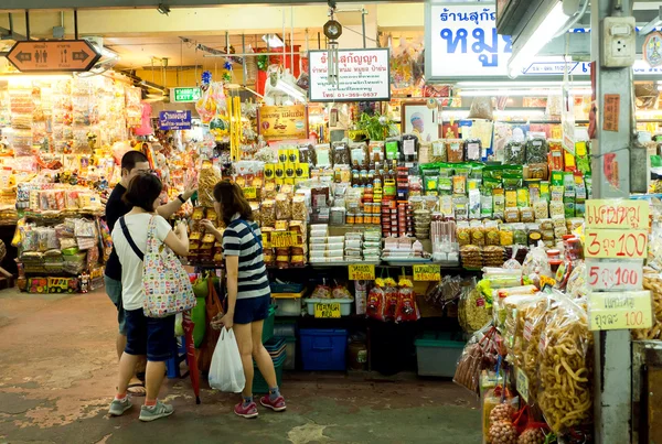 Jovens comprando alimentos exóticos no mercado com especiarias, carne, legumes frescos e doces — Fotografia de Stock