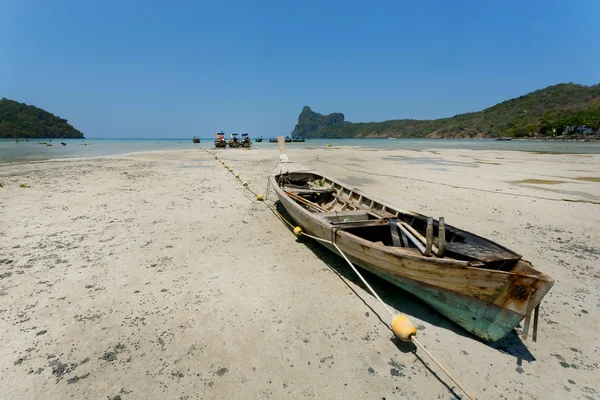 Barco de pescadores varados en zona seca de popular playa bajo cielo azul . — Foto de Stock