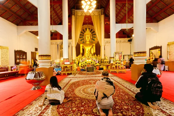 Άνθρωποι που προσεύχονται μέσα στην μεγάλη αίθουσα του ιστορικού ναού με το χρυσό άγαλμα του Βούδα — Φωτογραφία Αρχείου