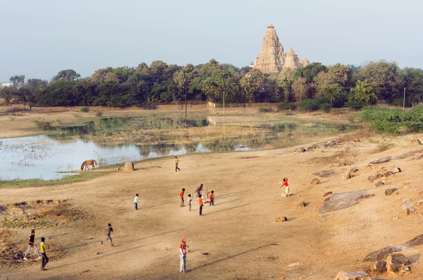 Paesaggio con tempio indù di Khajuraho e bambini che giocano a cricket, India — Foto Stock