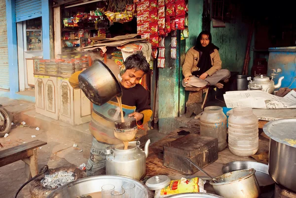 Criança ajudando a derramar o chá-masala em um café à beira da estrada na pobre rua indiana — Fotografia de Stock