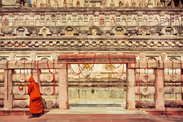 Τείχη του σκαλιστά ιστορικό ναό τόσο βουδιστές όσο και μοναχική κοντινή μοναχός στο κίτρινο κόκκινο φόρεμα κοντά στην πύλη, Ινδία. — Φωτογραφία Αρχείου