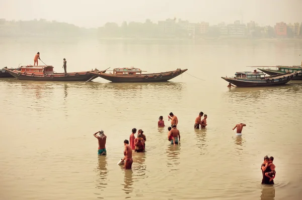 La gente se baña en el agua sucia del río indio más allá de los barcos de río — Foto de Stock