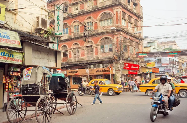 Езда на мотоцикле по оживленной улице с автомобильным движением и старинными рикшами — стоковое фото