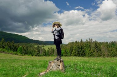 Bir ağaç kütüğü elinde fotoğraf makinesi ile ayakta, fotoğraf resim yapma genç turist kadın