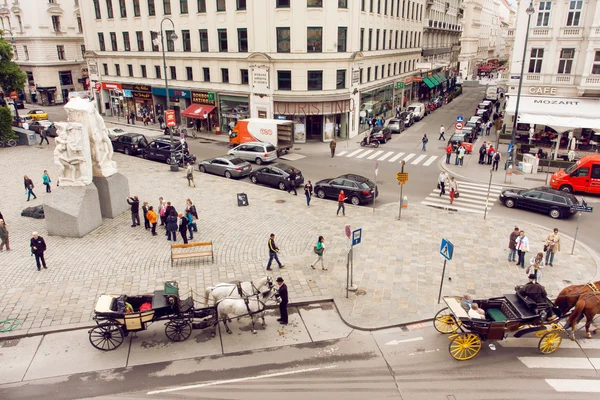 Multitud de turistas y otras personas caminando en la plaza de la ciudad con coches y edificios históricos — Foto de Stock