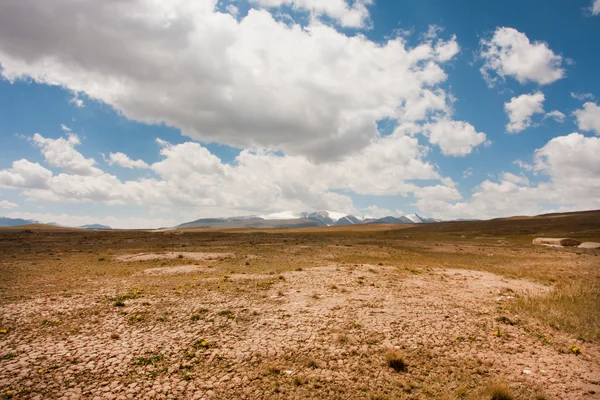 Low white clouds floating over dry land of the mountain plateau in Central Asia