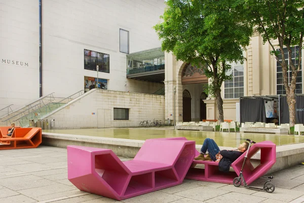 Hombre descansando en banco al aire libre en estilo moderno cerca del Museo Leopold — Foto de Stock