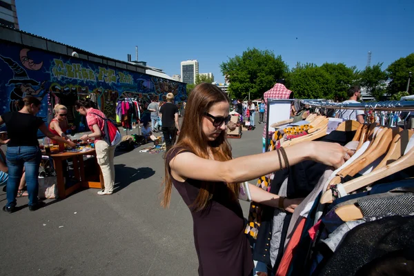 Girl looking for second hand dress and used items on the open air flea market — Stock Photo, Image