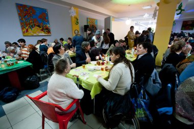 Poor people sit around tables at charity dinner