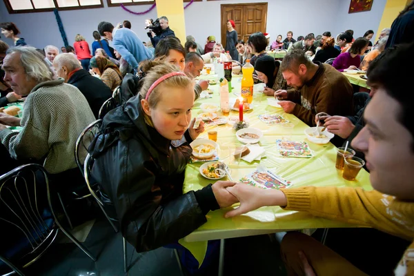 Poor people sit around tables at charity dinner