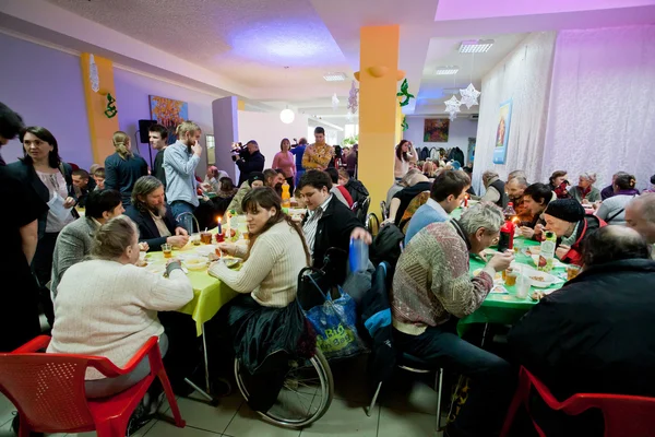 Poor people sit around tables at charity dinner