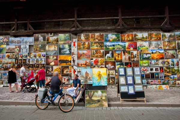 Tourists choose a picture on the market street of old town — Stock Photo, Image