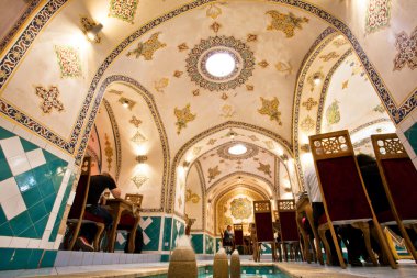 Tavandan ve desenli duvarları içinde insanlar yeme ile İran Restoran içinde