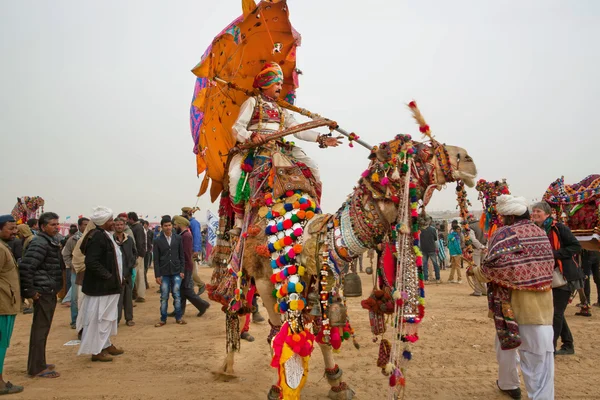 Colorful camel and rider with umbrella walking through the crowd — Stock Photo, Image