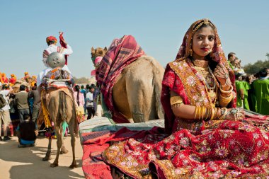 Girl with gold jewelry and traditional dress sit in camel cart