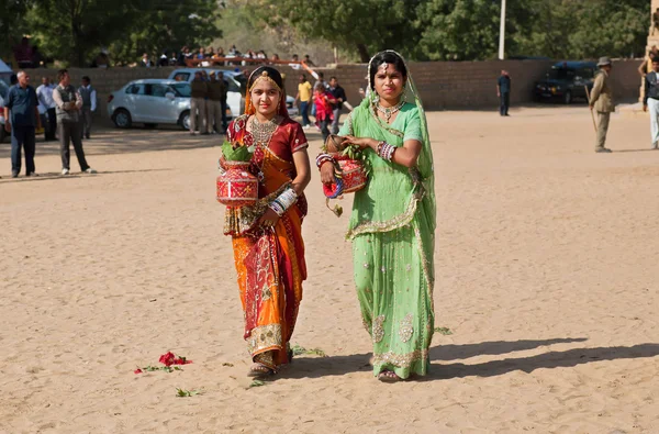 Две красивые одетые женщины, идущие на песчаное поле — стоковое фото