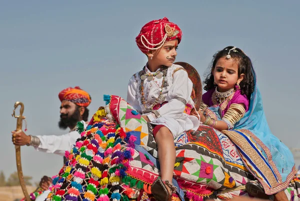 Мальчик и девочка ездят на верблюде на традиционном фестивале в пустыне — стоковое фото