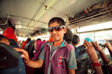 Çocuk birçok Hintli yolcu ile halk otobüsü içinde gülümseyen