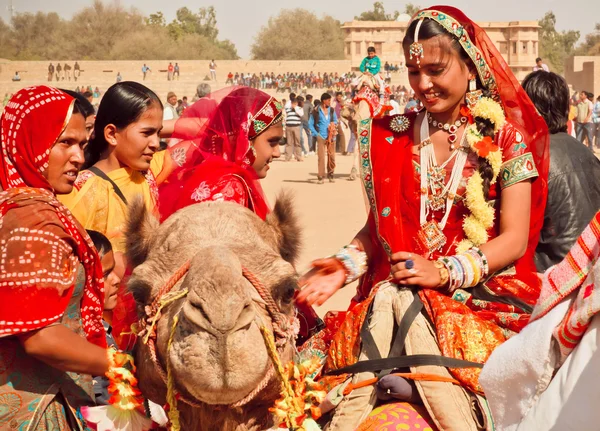 Joyeux visages de villageoises en sari rouge chevauchant les chameaux — Photo