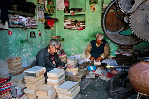 Två äldre arbetstagare reparerar gamla böcker i en verkstad — Stockfoto