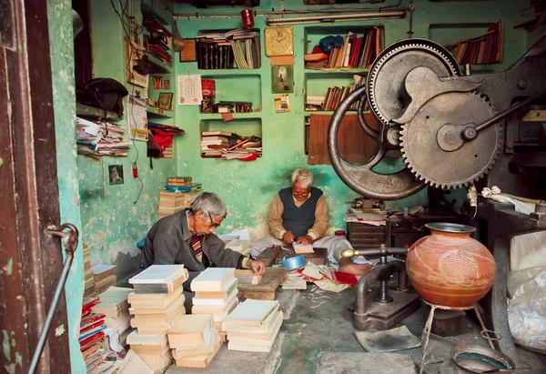 Two elderly workers repairing old books in a workshop — Stock Photo, Image