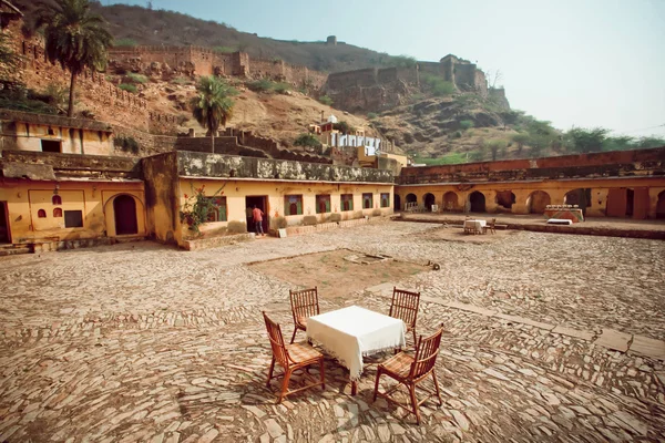 Lonely restaurant table in indian cafe under the fort walls and mountains — Stock Photo, Image
