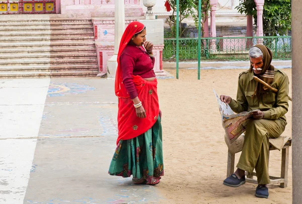 Indian woman and security officer reading a newspaper outdoor