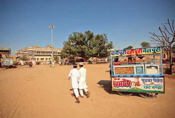 Two boys walking past dusty street kiosk with fast food on February 6 2015 in Rajas — Stockfoto