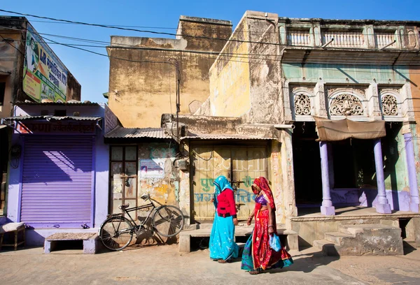 Two women in sari walking down the street with dilapidated houses — Stock Photo, Image