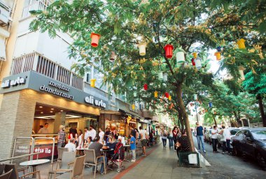 Visitors of outdoor cafe have breakfast in the shade