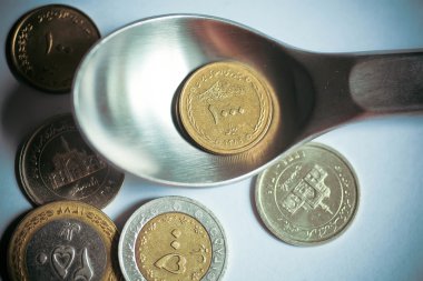 Selective focus on one thousand Iranian rials on a dinner spoon