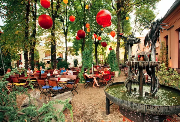 Outdoor cafe with people relaxing under street lamps — Stock Photo, Image