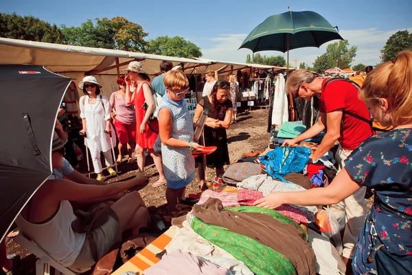 Foule de gens regarder vieux vêtements de seconde main marché — Photo